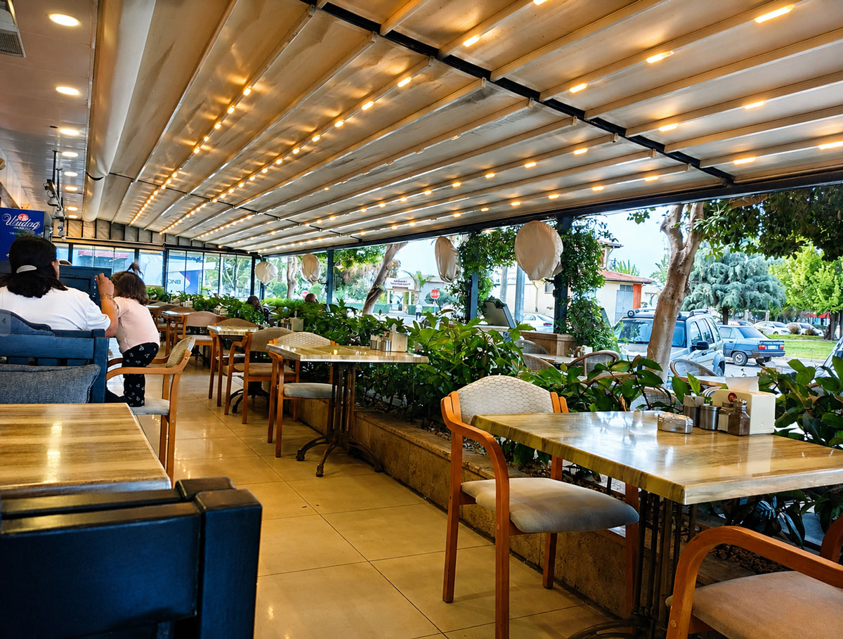 Chef Alaaddin kapalı terası, aydınlatmalı pergola altında masalar